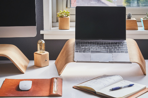 Monitor, laptop & mouse on white desk in front of gray wall and window. Liam Hennessy, Digital Strategist.