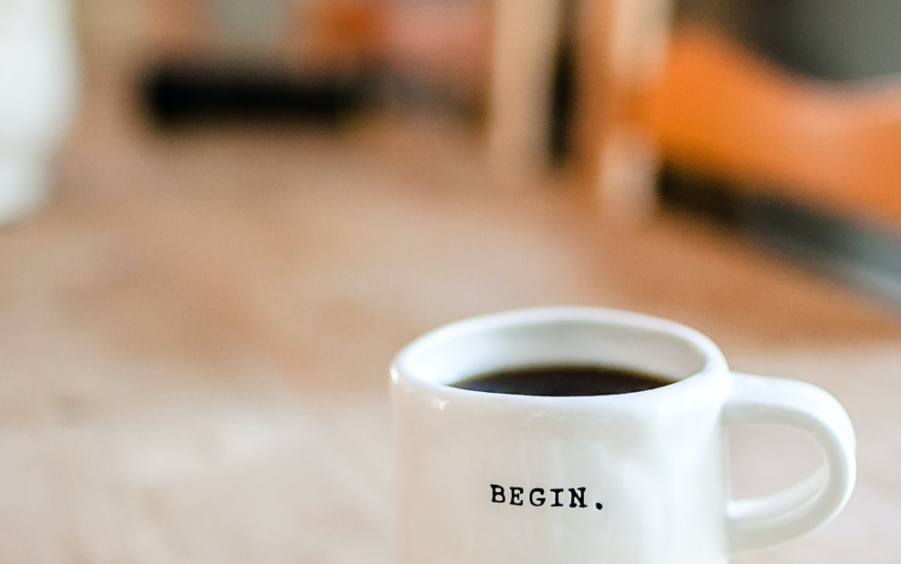 White cup with "begin" written on it. Liam Hennessy, Digital Strategist